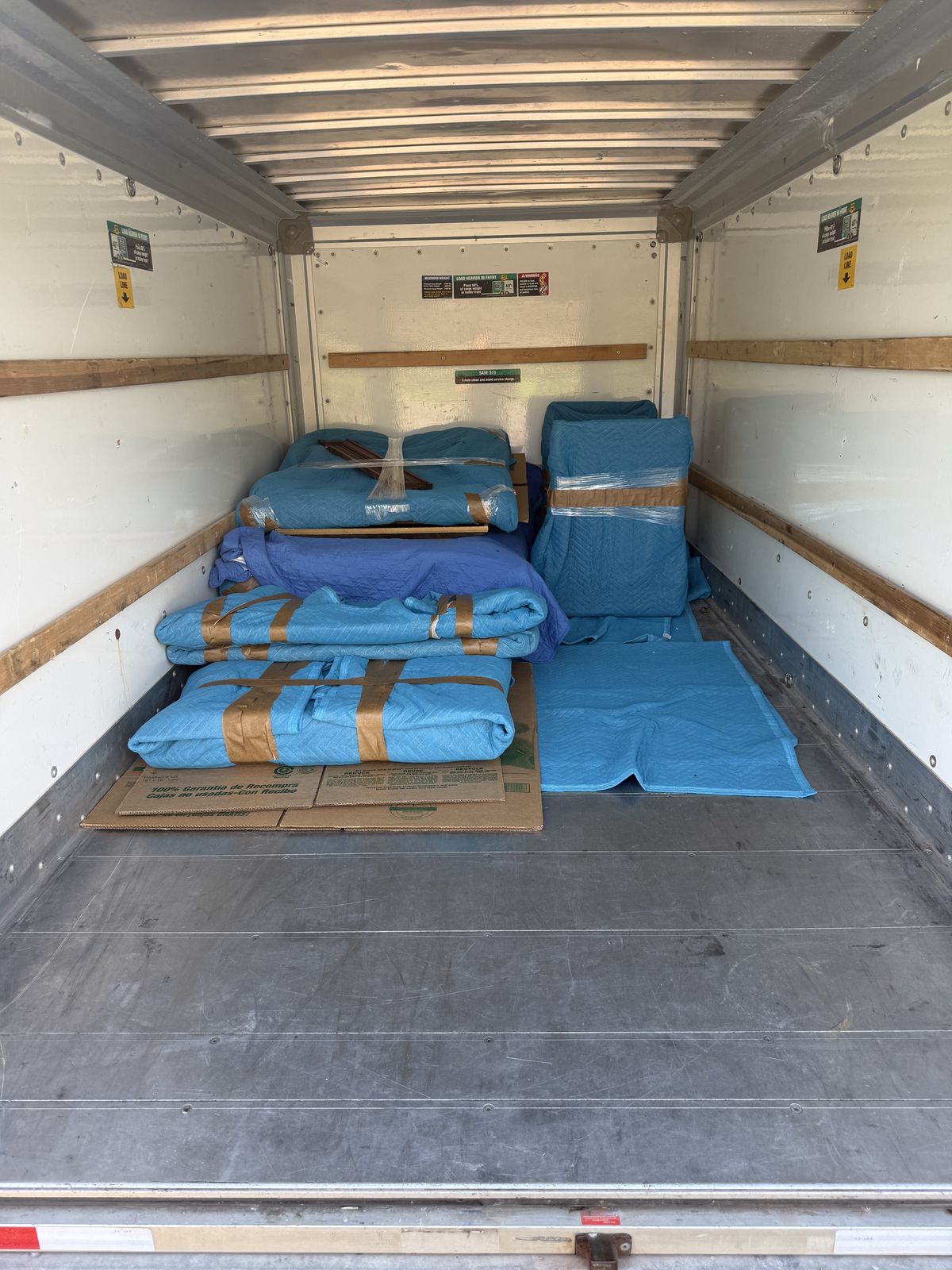 Inside a loaded box truck: pad-wrapped furniture stacked tight and banded so nothing shifts in transit
