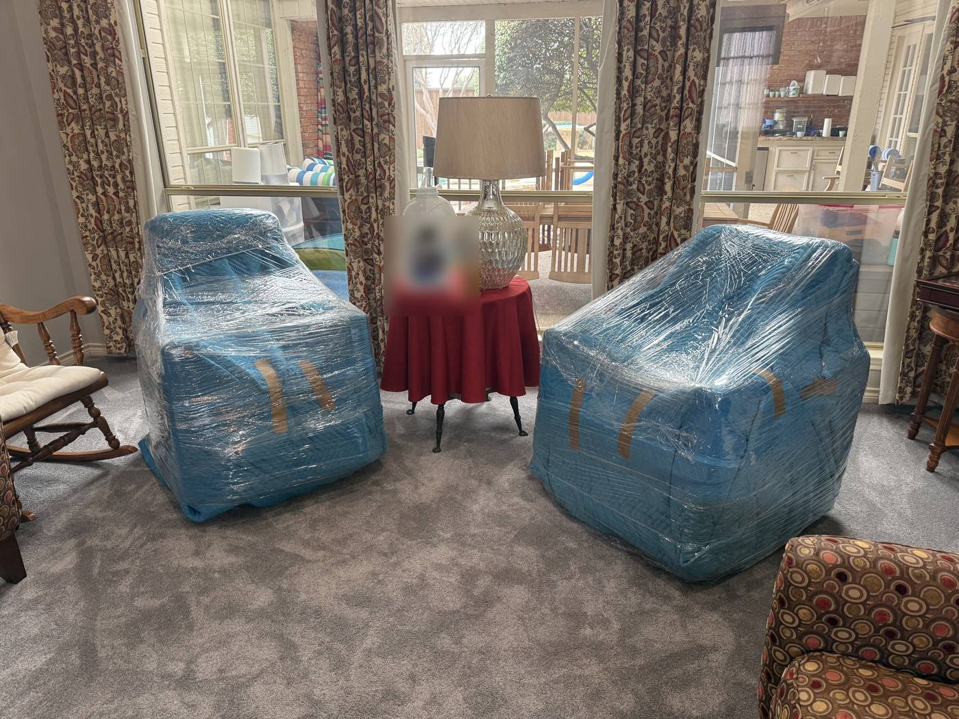 Upholstered armchairs blanket-wrapped and shrink-wrapped for a senior move, ready to leave a longtime family home